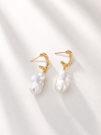 A professional studio shot of the Calliope earrings, showcasing the unique "flamed" texture and iridescent luster of the natural baroque pearls.