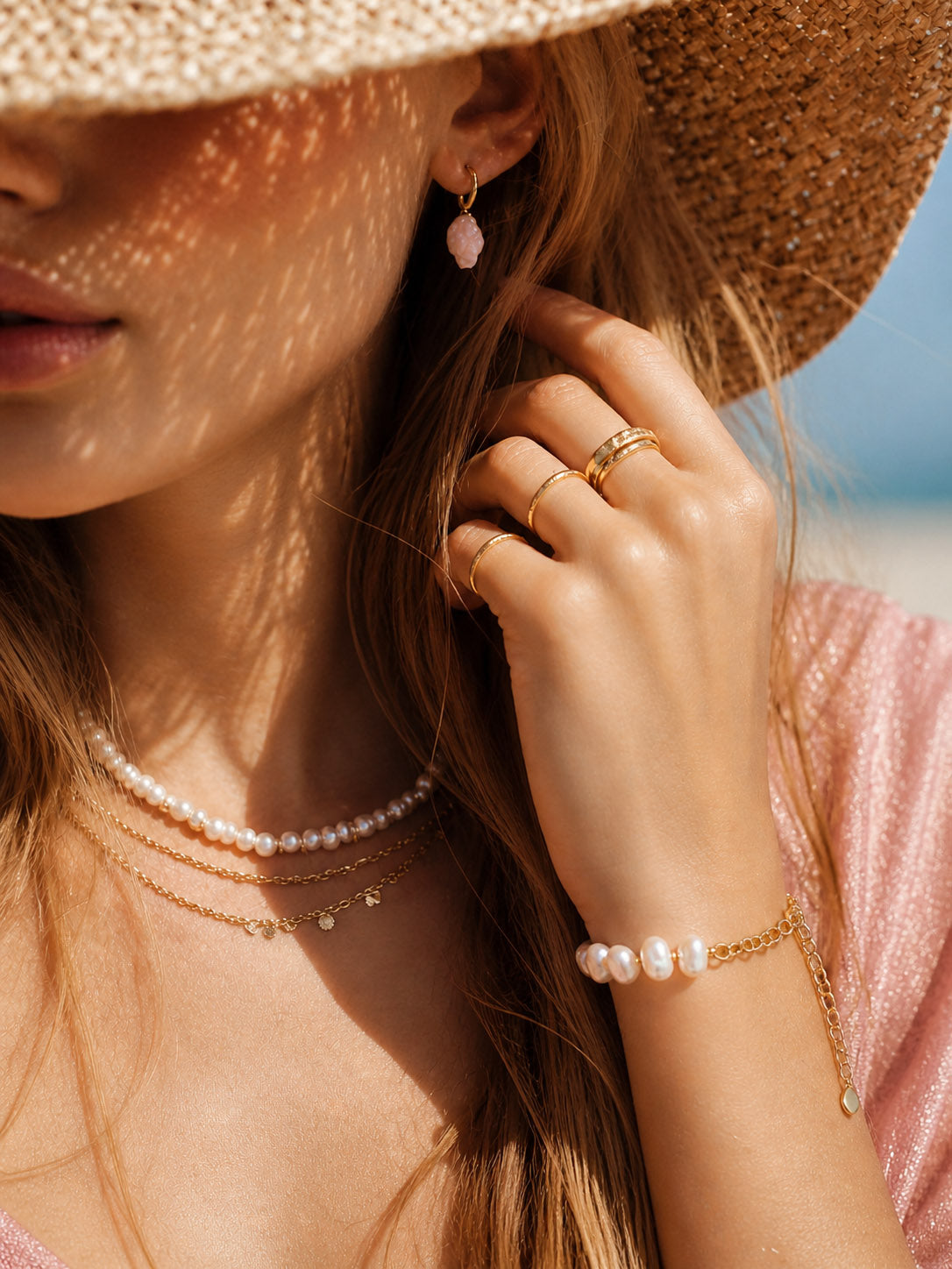 A lifestyle shot of the Astraea pearl link bracelet styled on a model's wrist, showcasing its delicate scale and how the 18K gold accents complement a warm skin tone.