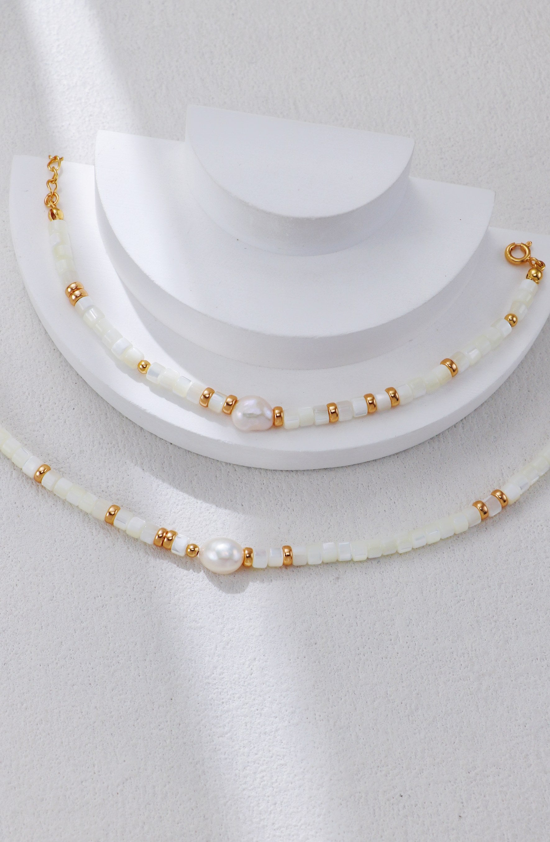 A macro close-up of the natural white shell beads, revealing their smooth, iridescent texture and high-quality finish. This visual reinforces the brand's focus on authentic marine materials.