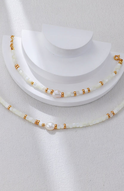 A macro close-up of the natural white shell beads, revealing their smooth, iridescent texture and high-quality finish. This visual reinforces the brand's focus on authentic marine materials.