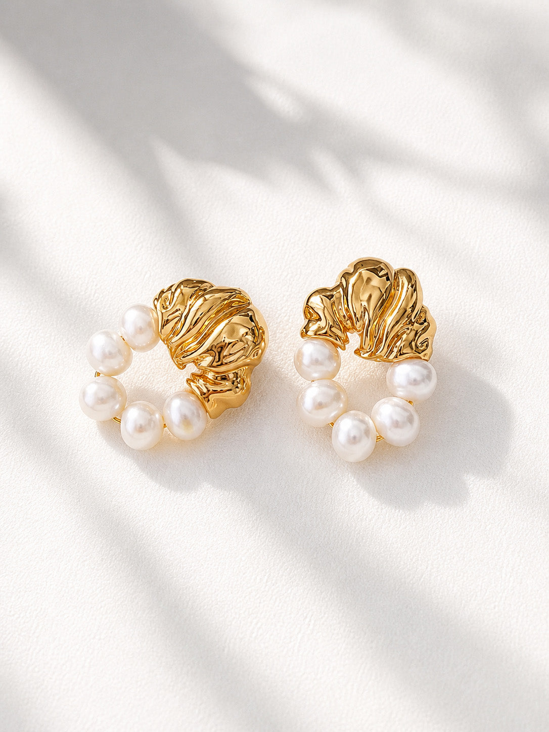 A professional studio shot of the Eos pearl drops, showcasing the distinct, irregular shapes of the natural freshwater pearls. This primary image highlights the S925 sterling silver quality and the radiant golden luster.