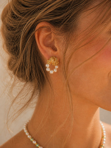 A lifestyle shot of the Eos baroque pearl earrings gracefully worn by a model. The visual emphasizes the elegant drop length and how the 18K gold-plated finish illuminates the face, perfect for modern bridal or high-end daily styling.