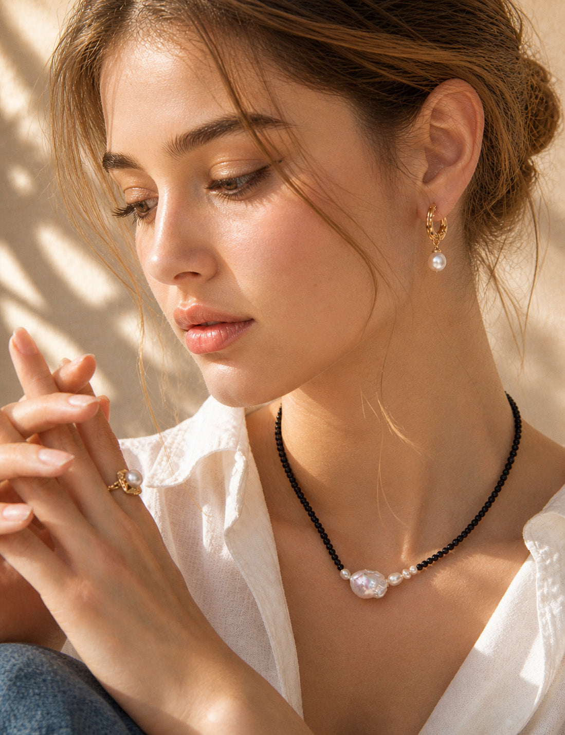 A lifestyle shot of the Sylva wood-textured pearl earrings worn by a model. The visual highlights the 3cm drop length and how the organic golden texture adds a warm, artisanal touch to a contemporary look.