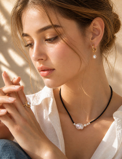 A lifestyle shot of the Sylva wood-textured pearl earrings worn by a model. The visual highlights the 3cm drop length and how the organic golden texture adds a warm, artisanal touch to a contemporary look.