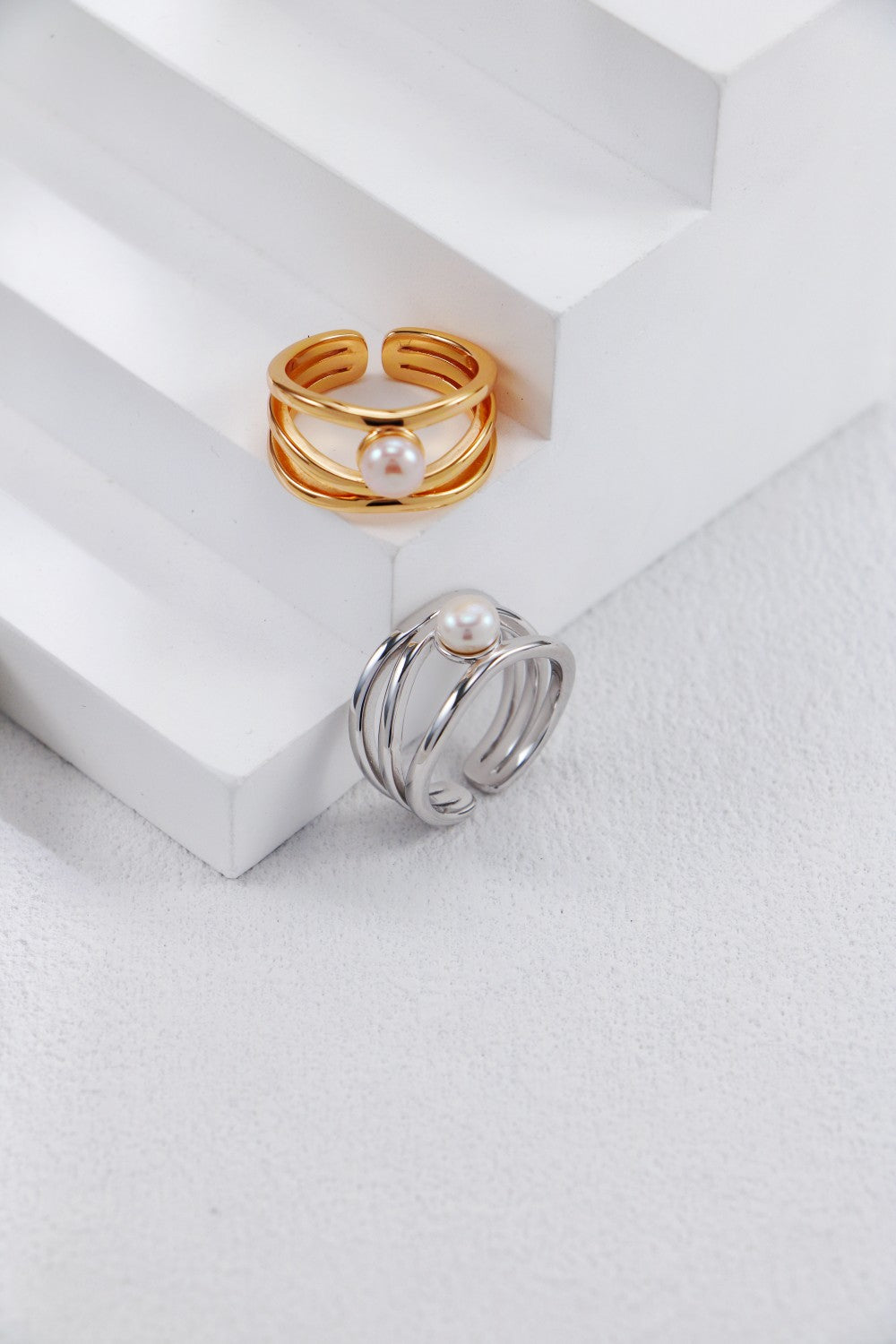 A beautiful overhead shot featuring both the Gold and Silver Clara rings, illustrating how the different finishes change the mood of the sculptural design.