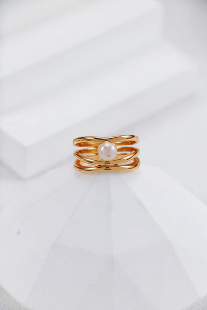 A professional studio shot of the Clara infinity pearl ring in vintage gold, highlighting the intricate interlaced band and the high-orient luster of the central pearl.