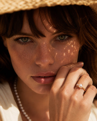 A lifestyle shot of the Elora pearl ring on a model's hand, demonstrating the flattering bypass silhouette and its effortless French-chic appeal.