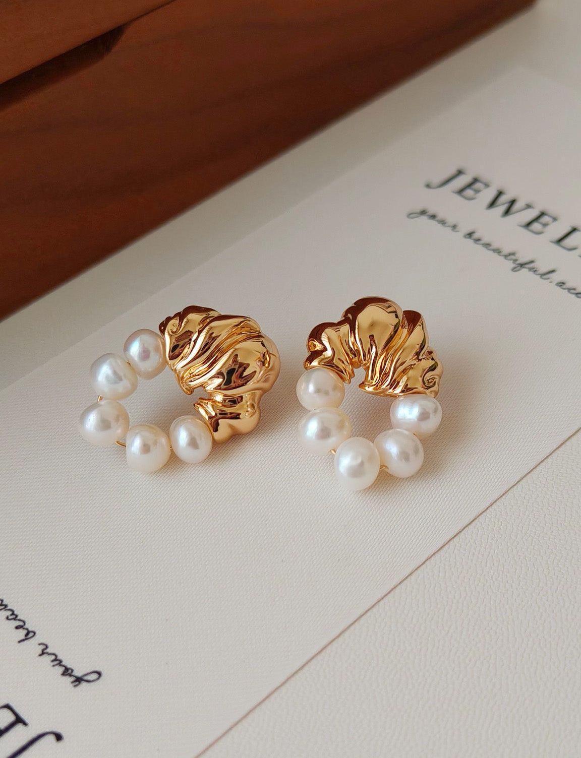 A clean profile view of the baroque pearl earrings, emphasizing the balance between the sculptural pearl and the secure golden setting, targeting searchers looking for one-of-a-kind artisan jewelry.