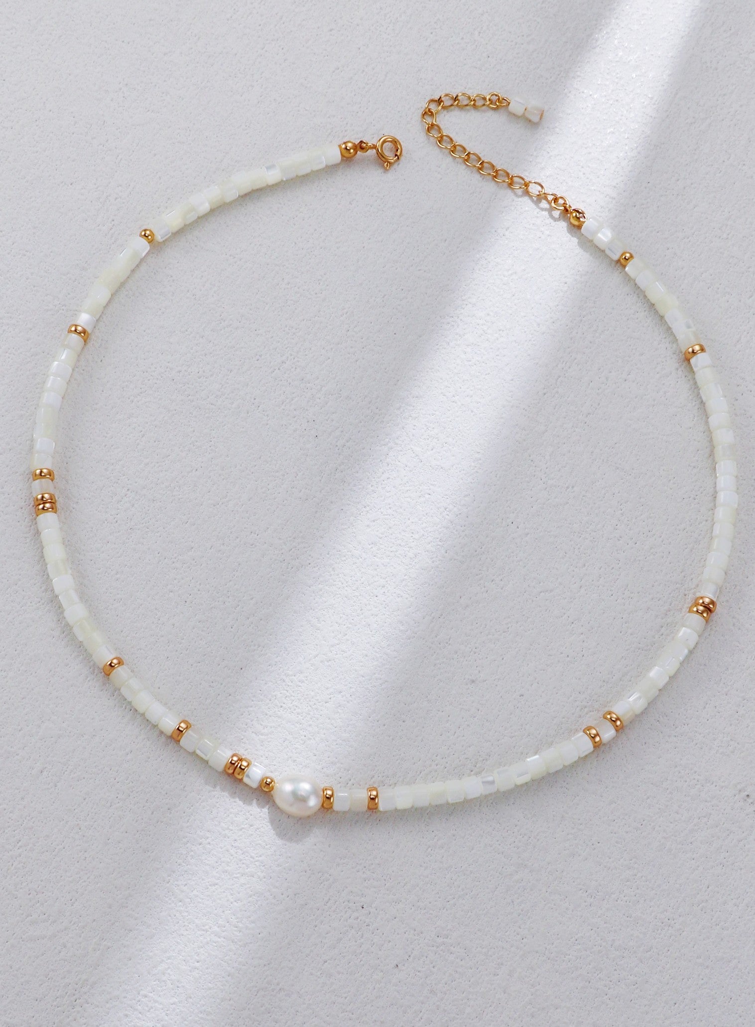 A clear studio shot of the Nereid necklace, displaying the singular focal pearl flanked by mother-of-pearl shell beads. This primary image emphasizes the S925 silver vintage gold craftsmanship and the organic white palette.