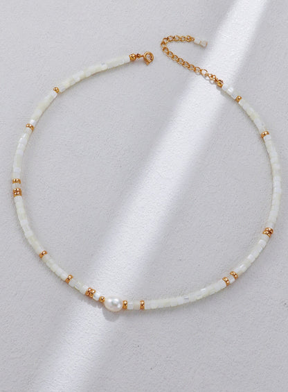 A clear studio shot of the Nereid necklace, displaying the singular focal pearl flanked by mother-of-pearl shell beads. This primary image emphasizes the S925 silver vintage gold craftsmanship and the organic white palette.