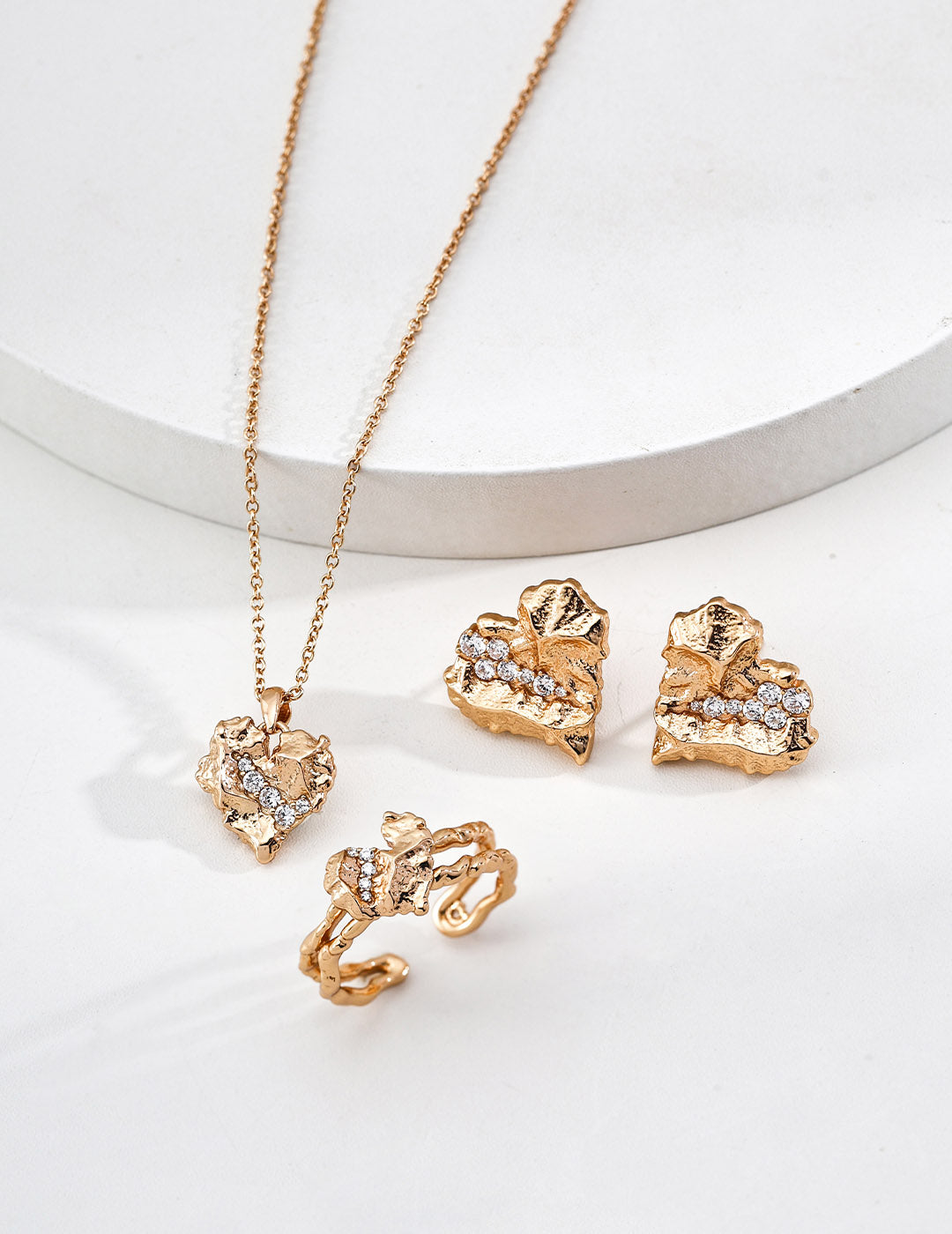 A lifestyle arrangement of the heart earrings alongside other gold accessories, showcasing their versatility for modern romantic styling.