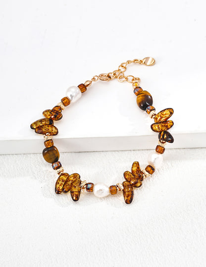 A clean studio shot of the Cybele bracelet, showcasing the eclectic mix of natural pearls, Czech glass, and Tiger's Eye beads on a vintage gold chain.