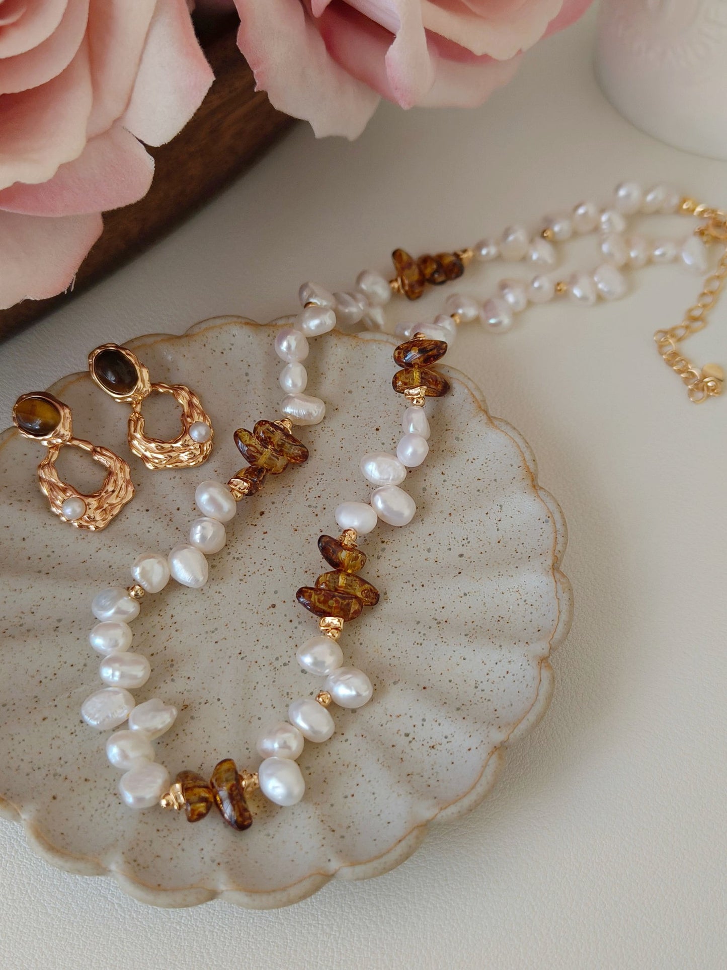 A detailed shot of the Tiger's Eye jewelry set displayed on a stone pedestal. This reinforces the "earthy luxury" theme and the brand's focus on natural gemstones and premium silver craftsmanship.