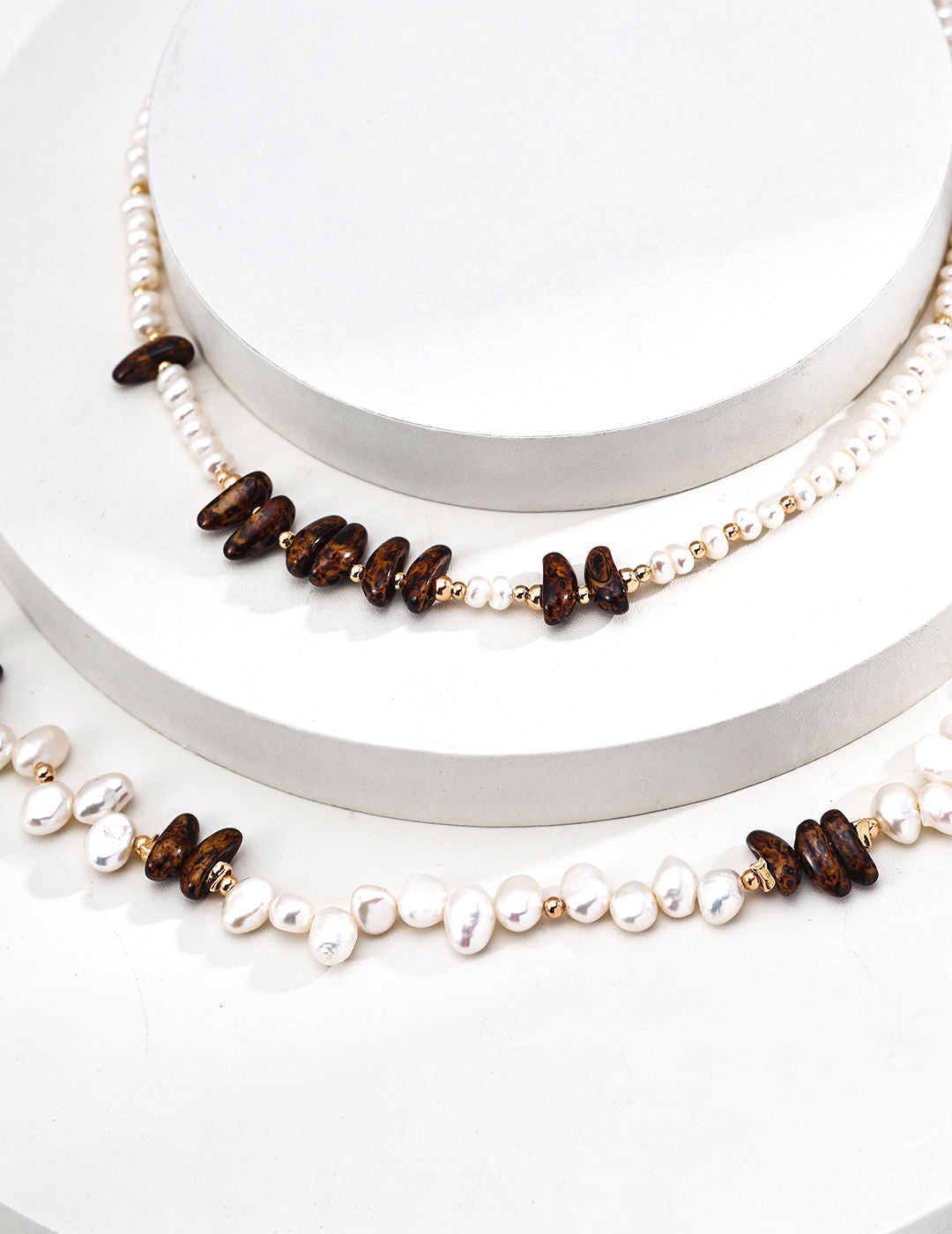 A macro close-up focusing on the unique "cat-eye" effect of the Tiger’s Eye and the organic texture of the baroque pearl. This visual targets customers looking for metaphysical gemstone jewelry with authentic, high-end finishing.