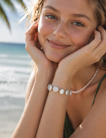 A lifestyle shot of the Theia baroque pearl bracelet on a wrist. The visual highlights the dramatic scale of the large central pearl and how the vintage gold finish adds a warm, heirloom quality to a modern look.