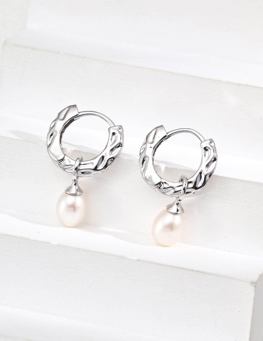 A professional shot of the Sylva earrings in Platinum Silver, emphasizing the sleek, modern feel of the S925 sterling silver and the cool-toned luster of the pearls.